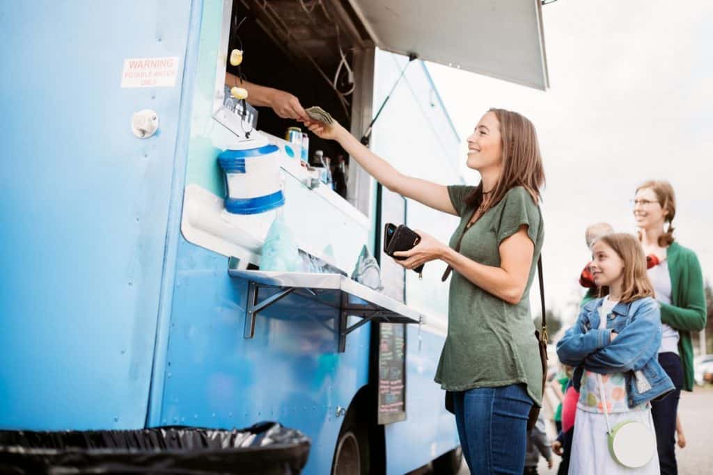 a person standing in front of a food truck