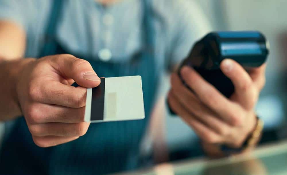 a person holding a credit card and a credit card reader